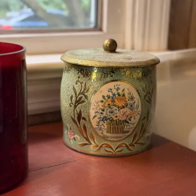 Sale Photo Thumbnail #187: Vintage lidded metal tin container featuring a crackle-finish floral design with gold accents.