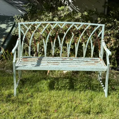 Sale Photo Thumbnail #247: Vintage light green metal garden bench with a decorative arched backrest, showing light surface rust and distress.