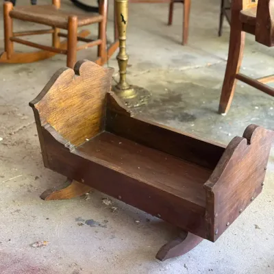 Sale Photo Thumbnail #270: Vintage handmade wooden doll cradle with shaped headboard and footboard, showing minor finish wear.