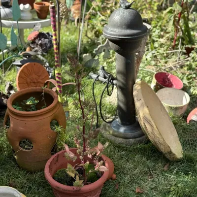 Sale Photo Thumbnail #251: Rustic metal birdbath fountain with a bird finial surrounded by various terracotta flower pots and garden ornaments.