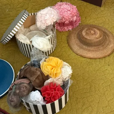 Sale Photo Thumbnail #38: Collection of vintage women's hats and millinery accessories, including floral pillbox hats, a woven straw sunhat, and fur accents stored in striped hat boxes.