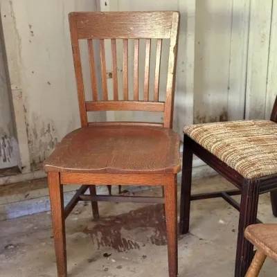 Sale Photo Thumbnail #281: Vintage oak slat-back desk chair featuring a contoured wooden seat and sturdy cross-bracing.