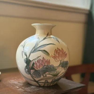 Sale Photo Thumbnail #88: Round ceramic vase featuring hand-painted Asian-style lotus flowers and leaves in soft pink and green tones.