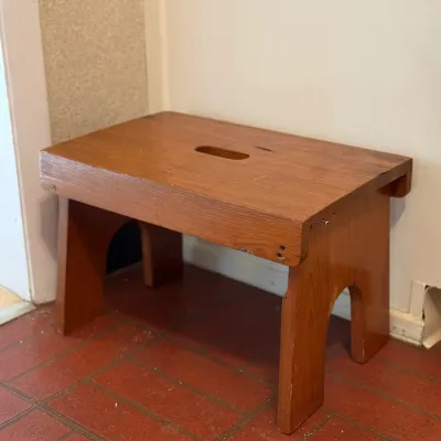Sale Photo Thumbnail #145: Simple wooden step stool with a hand cutout on top, showing light wear and screw construction.