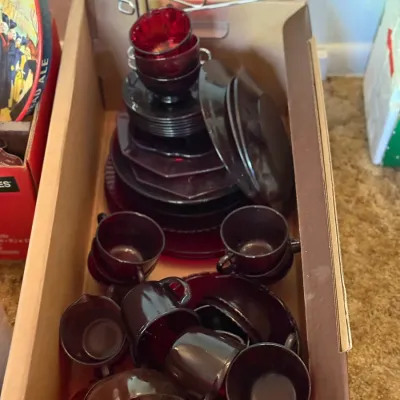 Sale Photo Thumbnail #66: Large set of vintage ruby red glass dinnerware packed in a cardboard box, including cups, saucers, and plates.