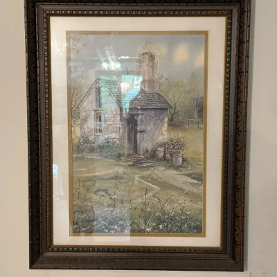 Sale Photo Thumbnail #158: Framed watercolor art print depicting a rustic stone cottage scene, presented in a dark carved wooden frame with a double mat.