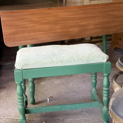 Sale Photo Thumbnail #291: Vintage green-painted bench with turned spindle legs and upholstered seat cushion, positioned in front of a wooden drop-leaf table.