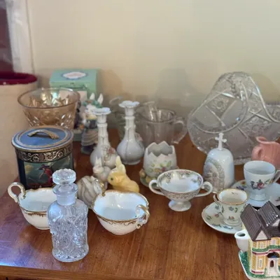 Sale Photo Thumbnail #71: Collection of vintage decorative glassware, ceramics, porcelain tea cups, and small figurines arranged on a wooden surface.