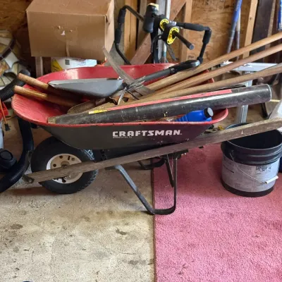 Sale Photo Thumbnail #219: Craftsman wheelbarrow filled with long-handled garden tools, shovels, and various yard equipment.