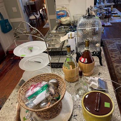 Sale Photo Thumbnail #11: Collection of kitchen and entertaining items displayed on a granite countertop, including a three-tiered frosted glass server, straw-wrapped wine bottles, a woven basket, a glass beverage dispenser, and various serving ware.