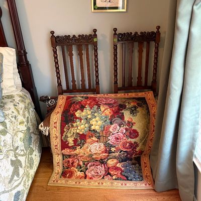 Sale Photo Thumbnail #47: Floral woven tapestry draped over a pair of vintage carved wooden dining chairs with spindle details.