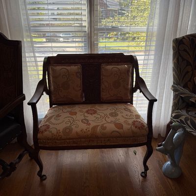 Sale Photo Thumbnail #22: Antique style carved wooden settee featuring floral pattern upholstery and cabriole legs, positioned in front of a window.