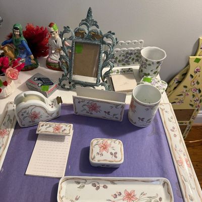 Sale Photo Thumbnail #45: Matching floral ceramic desk organization set including a tape dispenser, pen holder, letter holder, and trays, displayed alongside a ornate cast metal frame and small figurines.