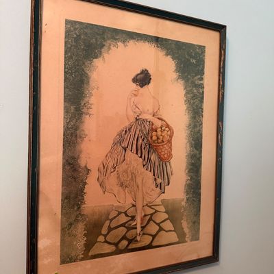 Sale Photo Thumbnail #49: Framed Art Deco style illustration print depicting a woman carrying a fruit basket, presented in a dark wooden frame with aged matting.