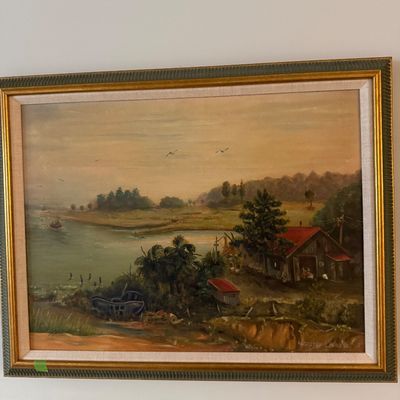 Sale Photo Thumbnail #73: Framed original oil painting depicting a coastal landscape with a cottage, boat, and river scene, set in a gold and green wooden frame.