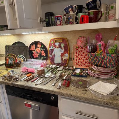 Sale Photo Thumbnail #79: Assortment of kitchenware and tableware, including various coffee mugs on cabinet shelves, serving trays, turkey decor, flatware, and colorful woven baskets.