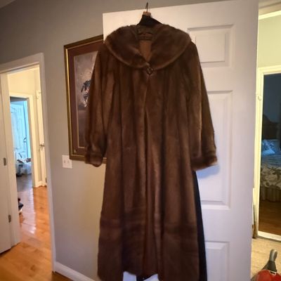 Sale Photo Thumbnail #60: Vintage full-length brown mink fur coat with a shawl collar, hanging on a door frame.