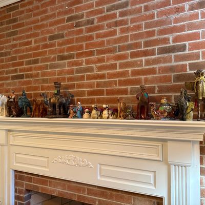 Sale Photo Thumbnail #35: Collection of decorative camel figurines in ceramic, wood, and mixed media displayed along a fireplace mantel.