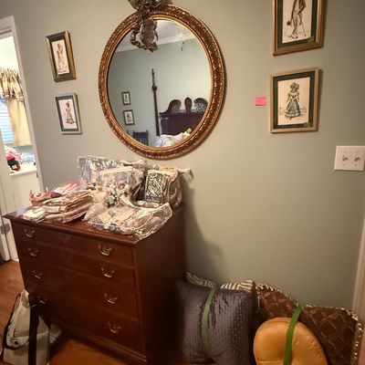 Sale Photo Thumbnail #59: Traditional dark wood chest of drawers with brass bail handles, topped with various craft supplies and framed artwork on the wall above.
