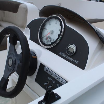 Sale Photo Thumbnail #47: Bayliner Element boat helm console featuring a black three-spoke steering wheel, central speedometer gauge, digital display, and toggle switch panel.