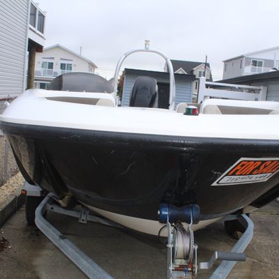 Sale Photo Thumbnail #49: Front view of a black and white motorboat resting on a metal boat trailer, featuring a 'For Sale' sign on the bow.