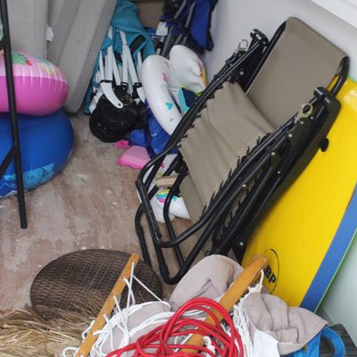Sale Photo Thumbnail #64: Collection of outdoor recreation gear including a yellow bodyboard, folded zero-gravity lounge chair, colorful inflatable pool floats, and additional beach accessories.