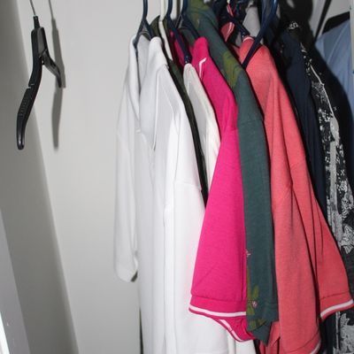 Sale Photo Thumbnail #75: Assorted men's short-sleeve polo shirts hanging on plastic hangers inside a closet rack.