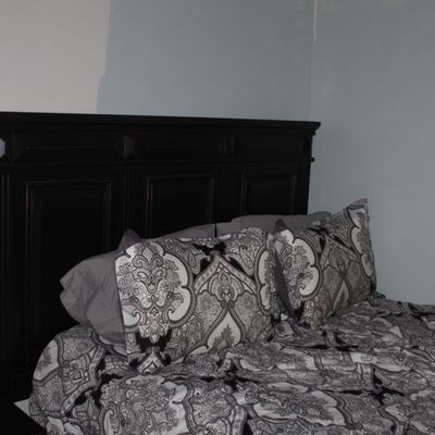 Sale Photo Thumbnail #69: Dark espresso-stained wooden king or queen size headboard with paneled detail, shown with matching patterned bedding and a modern rectangular table lamp.