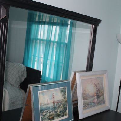 Sale Photo Thumbnail #86: Large dark wood dresser mirror with fluted side accents, paired with framed artwork and a floor lamp.