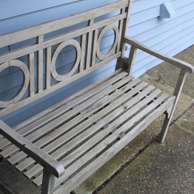 Sale Photo Thumbnail #41: Weathered wooden garden bench with a slatted seat and decorative circular backrest motifs, showing light outdoor wear.