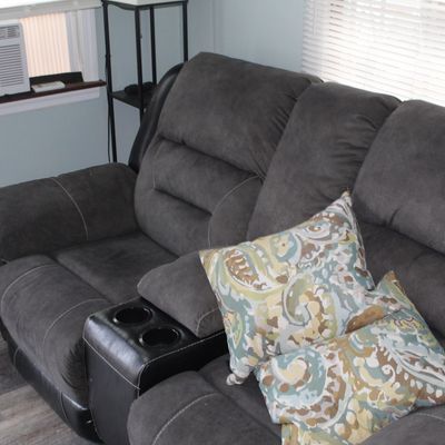 Sale Photo Thumbnail #22: Contemporary dark gray microfiber reclining sofa featuring a central console with dual cup holders and storage.