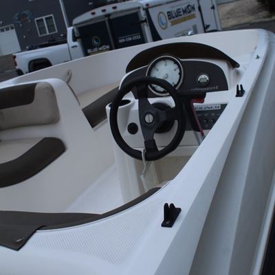 Sale Photo Thumbnail #46: Interior view of a modern Bayliner Element deck boat, featuring a white fiberglass hull with dark grey upholstery and a central helm console.