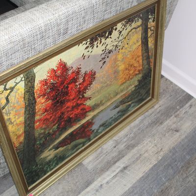 Sale Photo Thumbnail #14: Framed autumn landscape oil painting depicting vibrant red and orange foliage along a stream, set in a metallic gold-toned wood frame.
