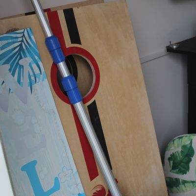 Sale Photo Thumbnail #65: Pair of wooden cornhole boards alongside an adjustable extension pole and a tropical-patterned welcome sign.