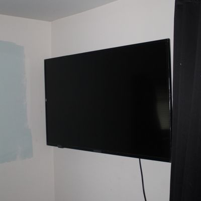 Sale Photo Thumbnail #71: Wall-mounted modern flat-screen television with a black bezel, positioned in the corner of a room.