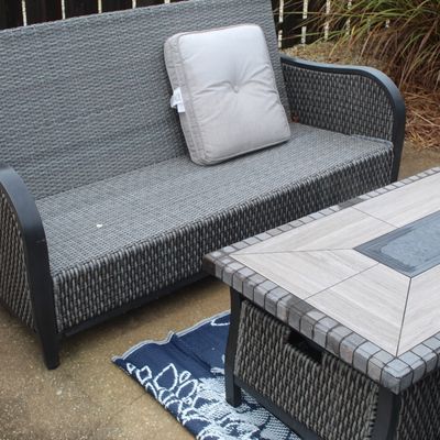 Sale Photo Thumbnail #54: Modern outdoor patio set featuring a gray resin wicker loveseat with a single accent cushion and a matching tile-top fire pit table.
