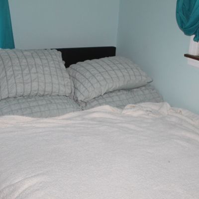 Sale Photo Thumbnail #88: Full or queen-size bed set featuring a dark headboard, textured light blue bedding, and a plush cream blanket.