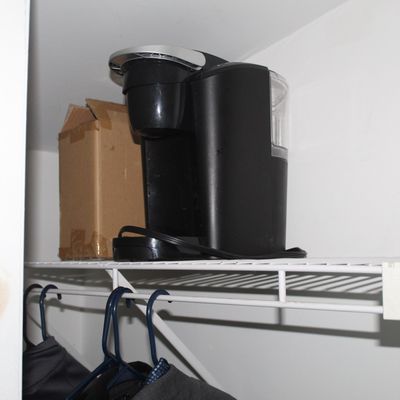 Sale Photo Thumbnail #36: Black Keurig single-serve coffee maker sitting on a closet shelf next to a small cardboard box.