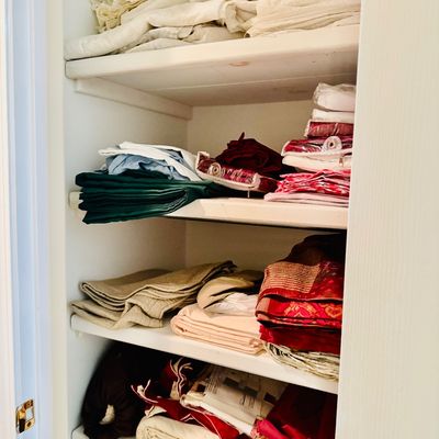 Sale Photo Thumbnail #50: Linen closet stacked with various fabrics, table linens, blankets, and textiles.