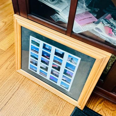 Sale Photo Thumbnail #31: Framed sheet of US 34-cent scenic postage stamps featuring Mt. Shasta, mounted under glass in a light oak wooden frame.
