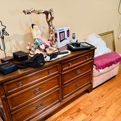 Sale Photo Thumbnail #52: Traditional wooden chest of drawers topped with a porcelain figurine, a Philips digital photo frame in box, small electronics, and camera bags.