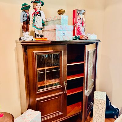Sale Photo Thumbnail #56: Traditional wooden display cabinet with leaded glass panels, topped with vintage collectible dolls in traditional costumes and boxed items.