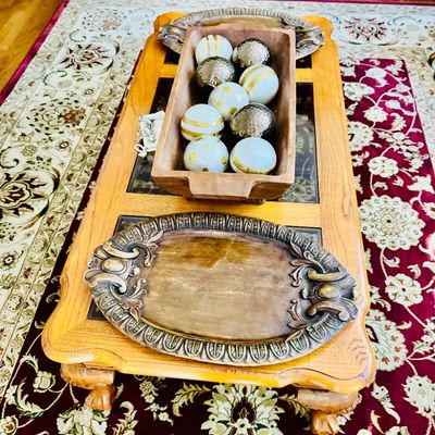 Sale Photo Thumbnail #3: Wooden dough trough filled with decorative spheres sitting on a light oak coffee table with an ornate metal serving tray.