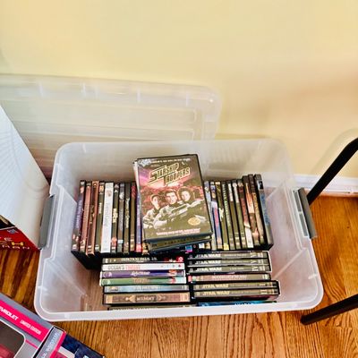Sale Photo Thumbnail #28: Large clear plastic storage bin filled with late 1990s and 2000s DVD movies, including titles like Starship Troopers, Star Wars, and The Mummy.