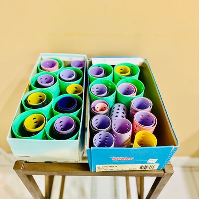 Sale Photo Thumbnail #67: Collection of colorful vintage plastic hair rollers organized inside two cardboard shoe boxes resting on a metal stand.