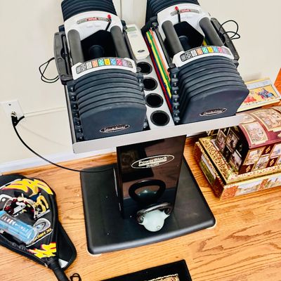 Sale Photo Thumbnail #40: Pair of adjustable PowerBlock dumbbells with matching stand, featuring color-coded weight selection indicator.