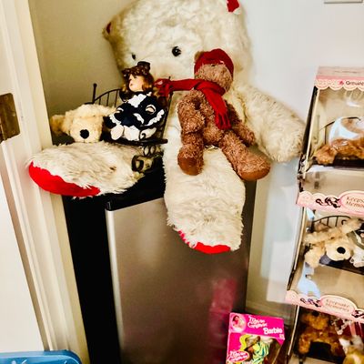 Sale Photo Thumbnail #84: Large white plush polar bear seated atop a compact refrigerator alongside smaller teddy bears, a porcelain doll, and boxed vintage collectibles including Barbie.