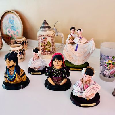 Sale Photo Thumbnail #36: Collection of Daniel's Collection Panamanian figurines depicting traditional pollera dress, alongside a lidded beer stein and small ceramic mugs.