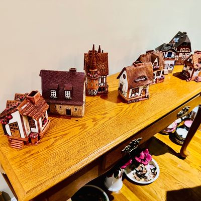 Sale Photo Thumbnail #26: Collection of ceramic European-style cottage and village miniatures displayed on a traditional oak sofa table.