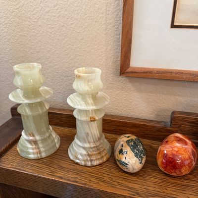Pair of vintage green onyx candlestick holders displayed alongside two polished stone decorative eggs on a wooden shelf.